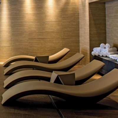 Четыре бежевых шезлонга в зоне отдыха с белыми полотенцами и мягким освещением